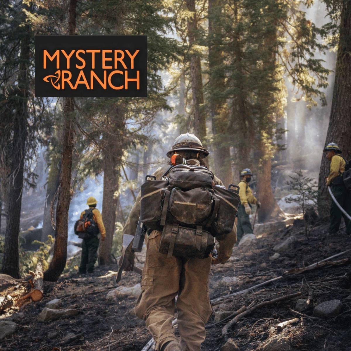 Wildland firefighters in forest terrain carrying Mystery Ranch backpacks during field operations.