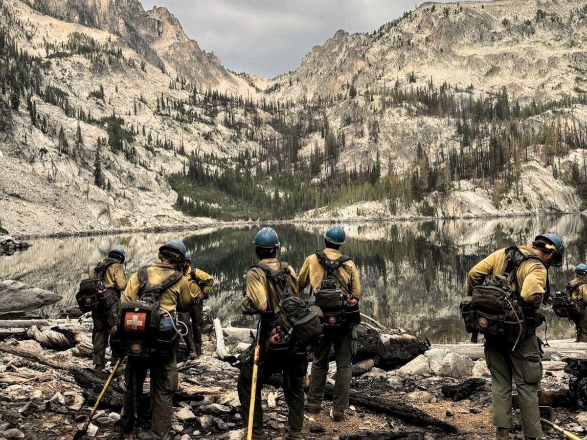Group of firefighters in a mountainous area with a lake in the background