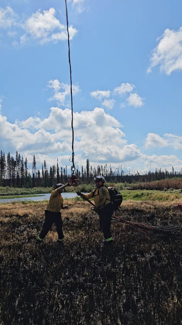 Australian wildland firefighters guiding suspended equipment in a burned field with Mystery Ranch packs.