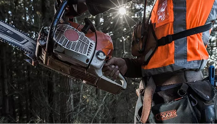 Person holding a chainsaw in a forest setting