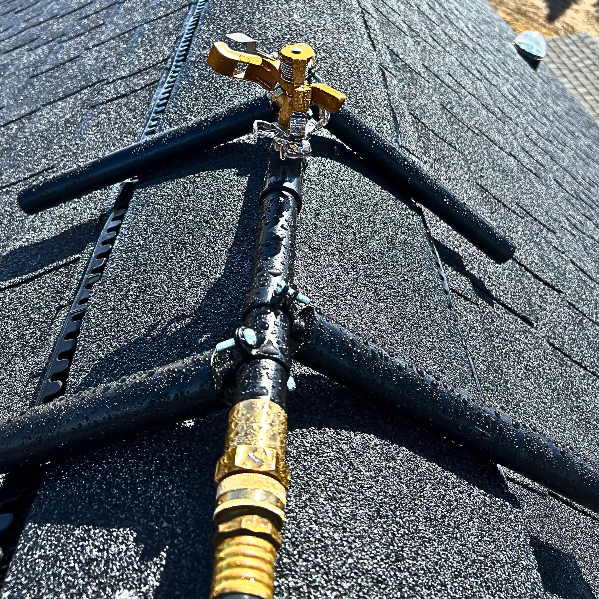 Rooftop sprinkler head mounted for exterior wildfire ember defense on residential roofs.
